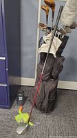 Photo of golf bag standing upright showing multiple golf clubs inside, MEC water bottle beside it, snorkel set on floor