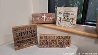 Four rustic style wooden holiday signs with thick edges displayed on a window sill