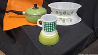 Green enamel saucepan, white Glasbake casserole, Fire-King white milk glass mug with green squares, and Fire-King green gradient milk glass bowl