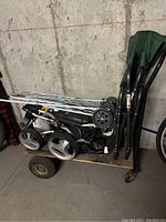 Side view of folded collapsible golf caddy, folding chair, and wooden wheeled cart.