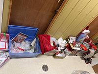 Wide view of assorted Christmas decorations and items packed in blue bins and laid out on floor showing various shapes and packaging.