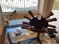 View of the utensil holder holding eight carved wooden handle cutting utensils alongside two decorative airplane figurines on a glass table by window.