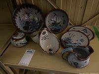Seven Mexican pottery serving dishes arranged on shelving, showing various shapes and sizes with hand-painted blue and green floral and bird motifs.