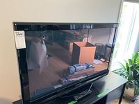 Panasonic 42-inch plasma HDTV shown on a black TV stand with a remote and power cord on the shelf below.