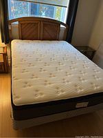 Full view of queen size bed assembled with mattress and boxspring, wooden headboard visible with chevron pattern and medium brown finish.