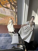 Two Royal Doulton figurines displayed on a window sill showing size and detail
