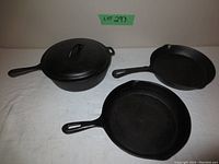 View of four cast iron pans including one with lid, showing front sides and handles.