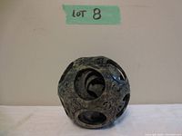 Front view of dark green carved stone dragon ball showing outer perforated layer with floral and dragon motifs