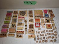 Photo of the full set of wooden craft stamps arranged on a white surface, showing all stamps including word phrases, patterns, and numbers.