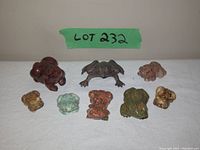 Photo showing all 8 frog and toad figurines arranged on a cloth with front perspective to display varying colors and sizes.