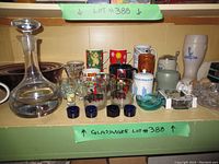 Full view of lot showing all glassware and décor items arranged together, highlighting decanter, mugs, steins, ashtrays, plate and small decorative glass items.