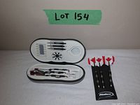 Two Helix dart sets displayed side by side on a white surface, showing the darts and their aluminum molded cases. One set with red maple leaf flights.