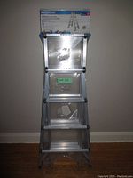 Full front view of sealed ladder in original packaging against wall