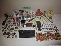 Full overview of the lot showing various small collectibles, pins, spoons, cases and patches spread on a white surface.