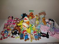 Wide view of various plush toys arranged on a table, showing Mario Bros, Pokemon, and other plush characters.