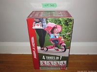 Front of sealed box showing child in red and pink stroller and “4 Trikes in 1”