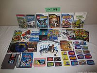 Full lot laid out on a bed surface showing Wii cases, Gameboy Advance cartridges, Sega Genesis cartridge, PSP game, and instruction booklets.