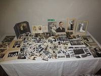 Full view of the entire lot spread out on a table showing many black and white vintage photos and several mounted portraits.