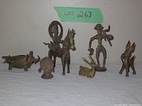 Photo showing the entire set of seven vintage bronze figures arranged on white cloth, each figure distinct in form and style.