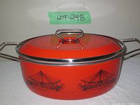 Side view of the orange enamel cooking pot showing Egyptian style ship prints and metal handles