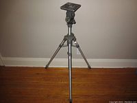 Full view of the vintage Majestic camera stand tripod with three adjustable legs and mounting plate on top, placed against a plain wall.