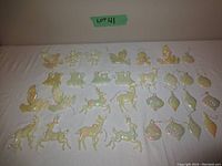 Photo showing the full lot of 34 vintage pearl finish Christmas ornaments spread out on a white surface, displaying variety of shapes including angels, birds, reindeer, trains, gingerbread men, boots and baubles.