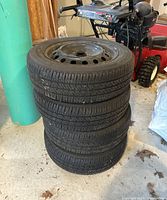 Four stacked tires with black steel rims, showing overall condition and size.