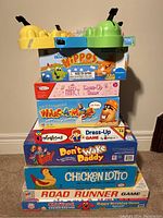 Stack of vintage children's games including Hungry Hungry Hippos, Chicken Lotto, Road Runner, Don't Wake Daddy, Dress-Up games and more.