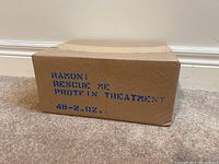 Closed brown cardboard box labeled with blue stenciled text 'RAMONI RESCUE ME PROTEIN TREATMENT 48 - 2.0 OZ.' indicating the lot contains 48 bottles of hair treatment.