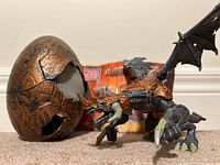 Photo showing copper-colored broken dragon egg, articulated black and copper dragon figure, and instruction sheet in background