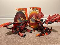 Two articulated Mega Bloks dragons posed seated with eggs behind them showing crack detailing and instruction sheets visible