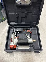 Paslode Lite-Line HP100 nailer inside fitted black plastic carrying case placed on floor.