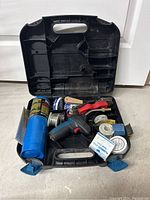 Open black plastic toolbox containing various plumbing tools and supplies including solder wire, flux, and a propane torch.