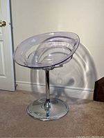 Side and front view of modern clear swivel chair showing seat and pedestal base.