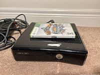 Black Xbox 360 S console with Skylanders Giants game case on top, visible cables attached.