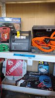 Shelf display of DieHard Portable Power 750 jump starter, orange jumper cables in black case, flammable sign, and boxed battery cables.