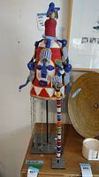 Front view of beaded head dress on stand with staff leaning alongside