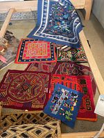 View of multiple Mola panels laid out on the floor showing their colors and designs.