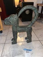 Side angle of metal panther sculpture showing textured body and curved tail.