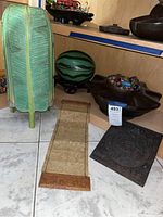 Photo showing green metal melon keeper, carved wooden bowl with colorful Nepalese bead jewelry, hanging fabric wall art and dark carved wooden panel, and green banana leaf shaped lamp shade.