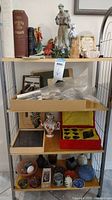 Metal shelving unit with multiple levels displaying religious books, figurines and decorative items