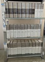 Three shelves showing cream and grey dust-jacketed volumes across all shelves