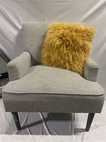 Front view of light grey fabric accent chair with yellow shaggy pillow, showcasing seat and armrests.