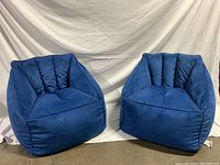 Front view of two blue kids beanbag seats on a plain backdrop.