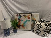 Full set featuring two framed geometric art prints, black and white cushions, blue table lamp, and faux plant in blue pot.