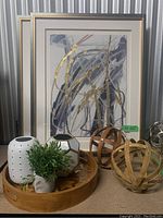 Overall view of framed art, wooden tray, decorative spheres, vases and plant
