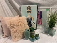 Wide view of decorative set including cushions, lantern lamp, faux plants, and framed art