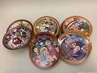 Ten Hedi Keller collectible plates arranged in groups showing colorful, detailed religious and nativity designs with wooden-look rims.