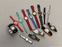 Photo showing 11 assorted quartz wristwatches in various colors and styles, arranged in a row.