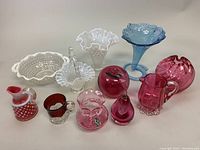 Full lot view, showing all 10 glass items including hobnail milk glass pieces, cranberry glasswares, blue blown glass vase, and decorative glass items